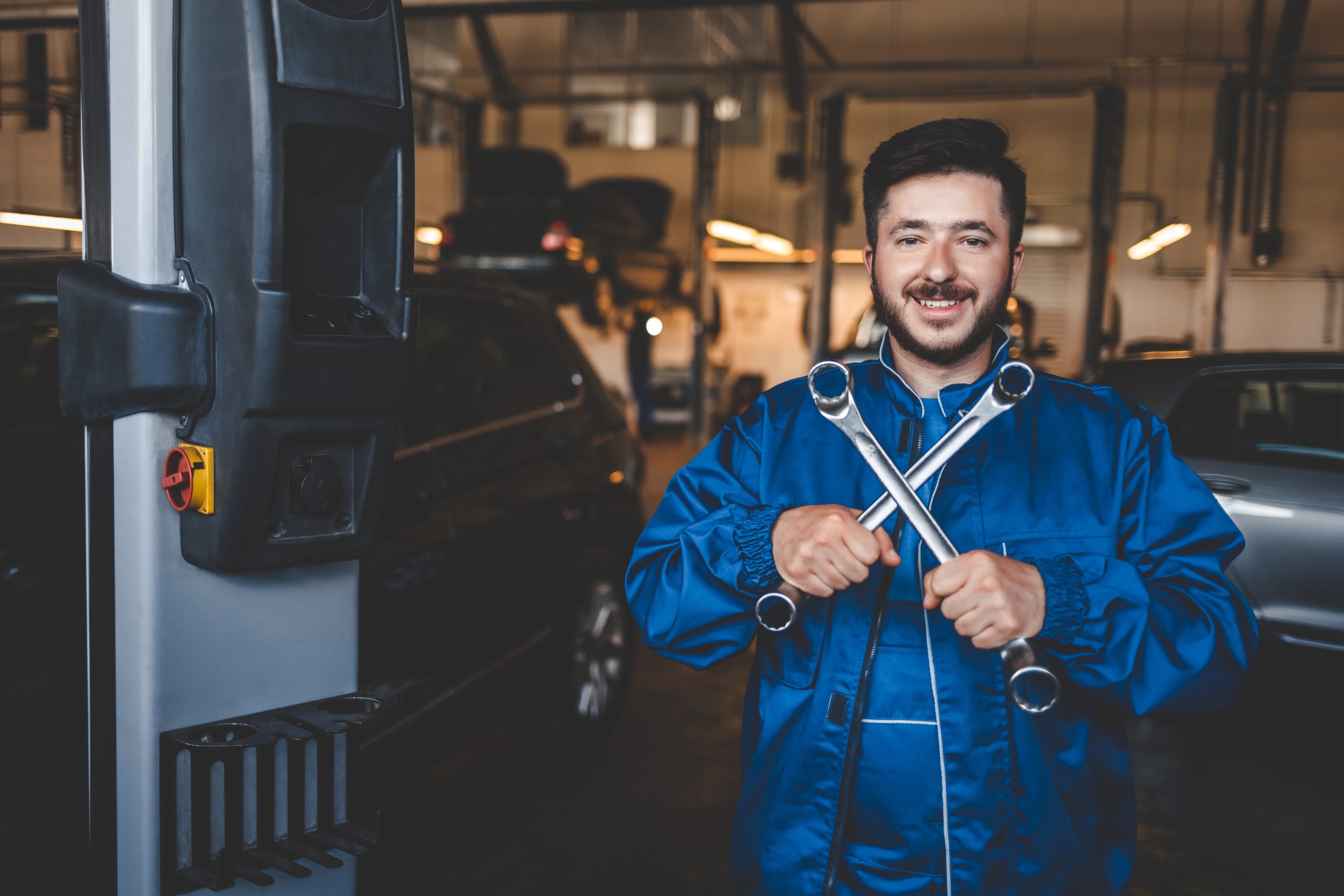 positive auto mechanic stands with wrenches in his hands car service c - Avigauto Recambios
